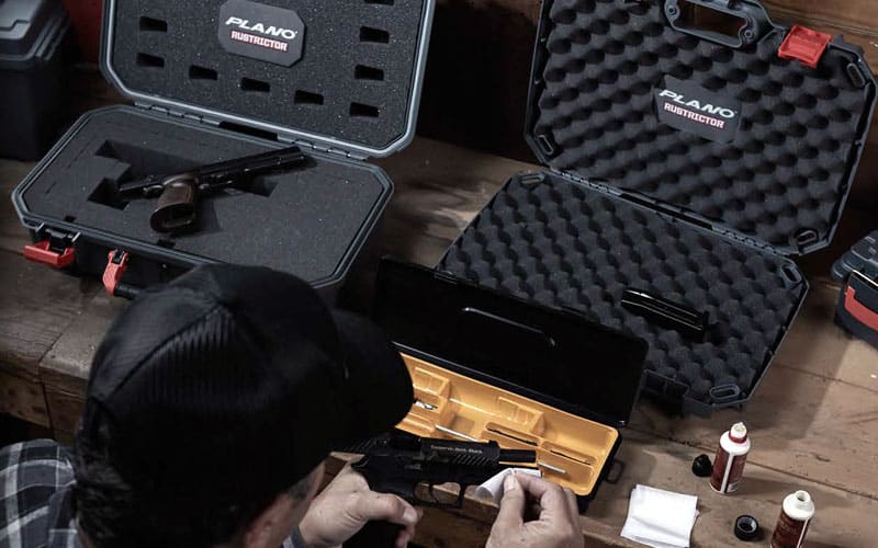 Shooter cleaning handgun on Plano Rustrictor Pistol Cases